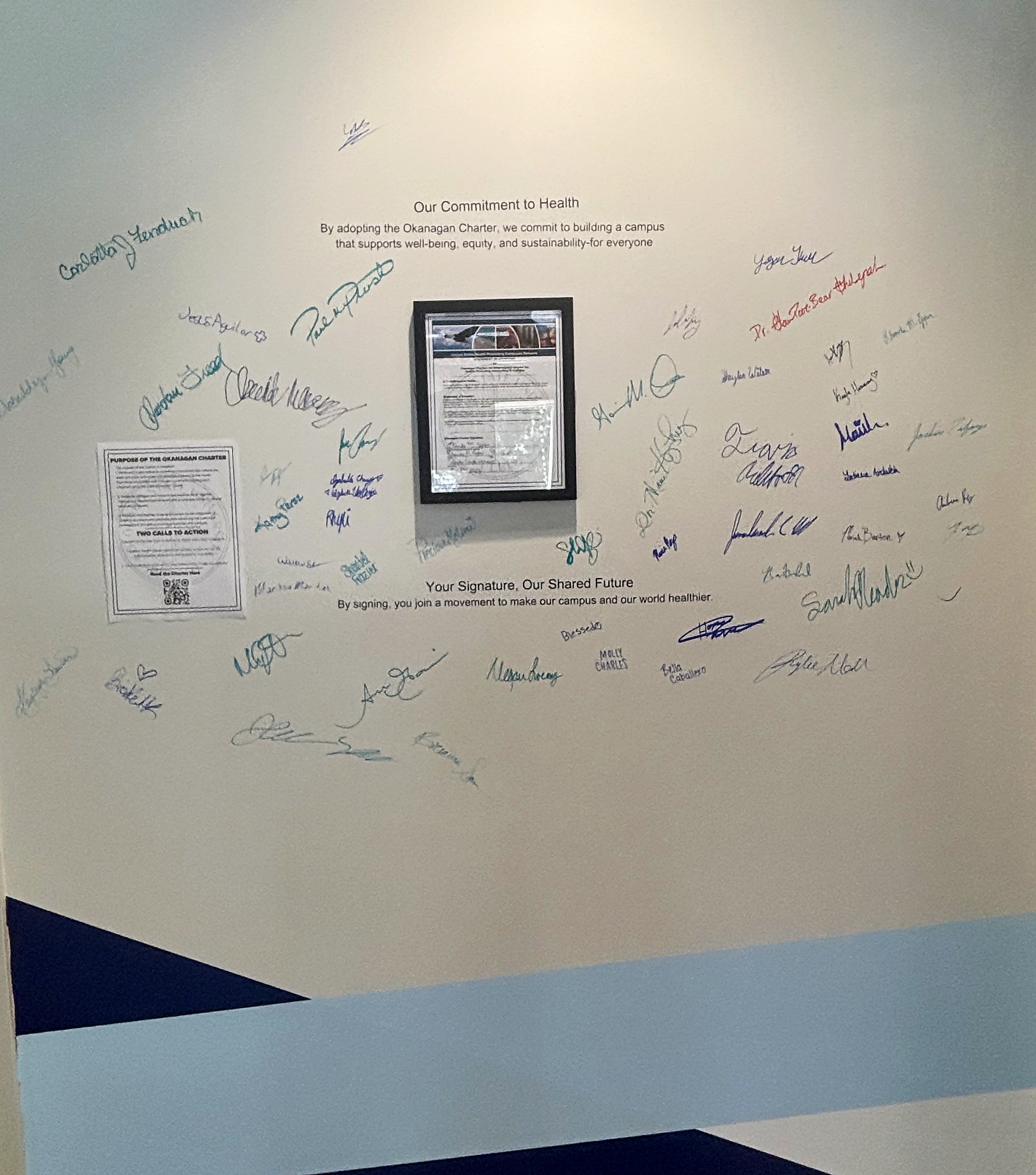 Faculty, staff and students add their names to the Okanagan Charter commitment wall inside the Occhiato Student Center.