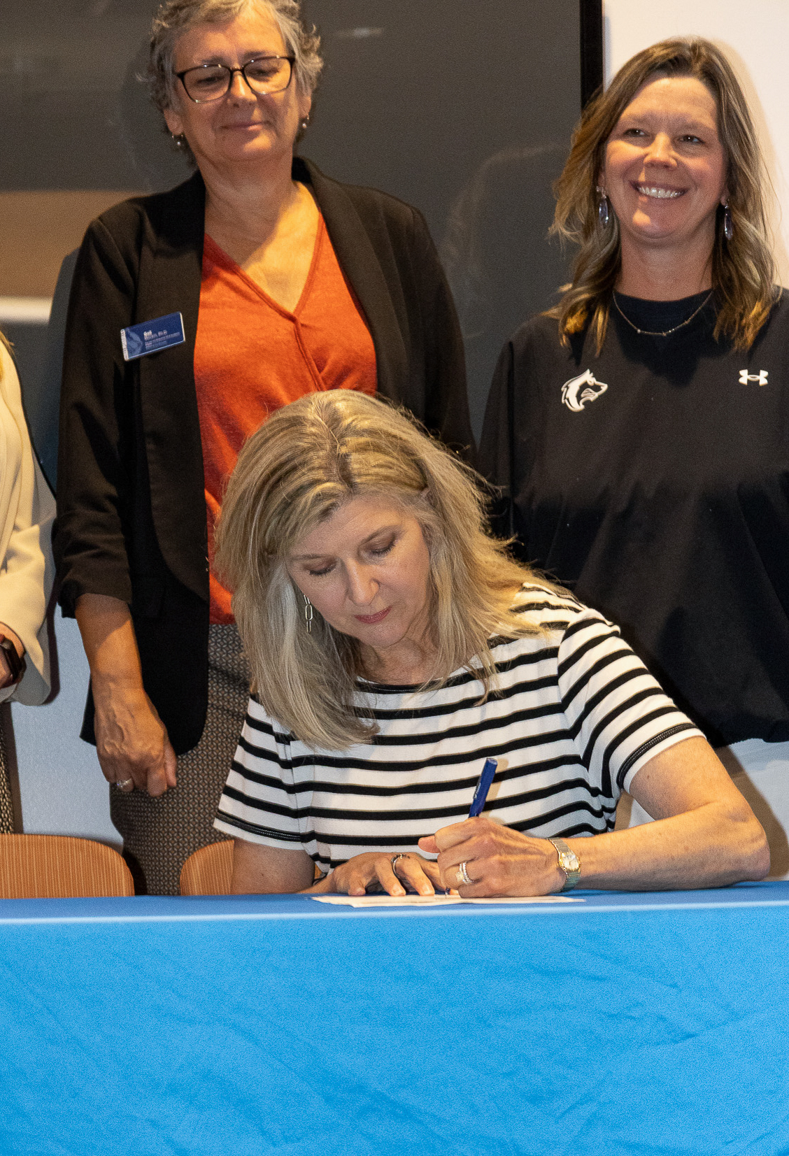 President Rhonda Epper signs the Okanagan Charter with Provost Gail Mackin and Kristyn White Davis behind her.